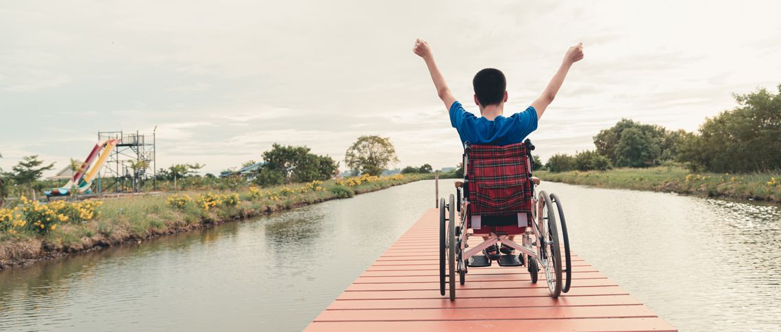 person in wheelchair with arms raised